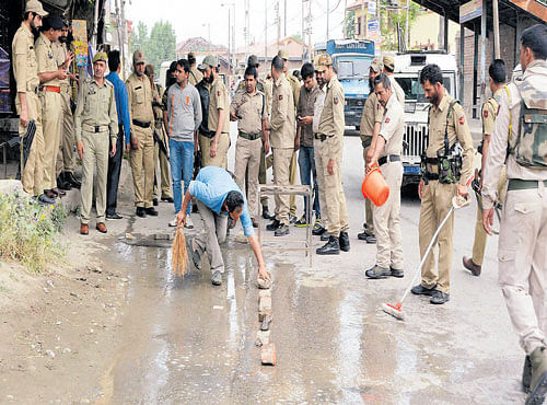 ATTACK SPOT: Police personnel wash blood off the spot where militants attacked a police post and killed two policemen at Zadibal Hawal in Srinagar on Monday. PTI