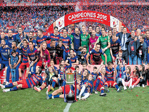 Champions: Barcelona players with the King's Cup after they beat Sevilla 2-0 at the Vicente Calderon on Sunday. Reuters