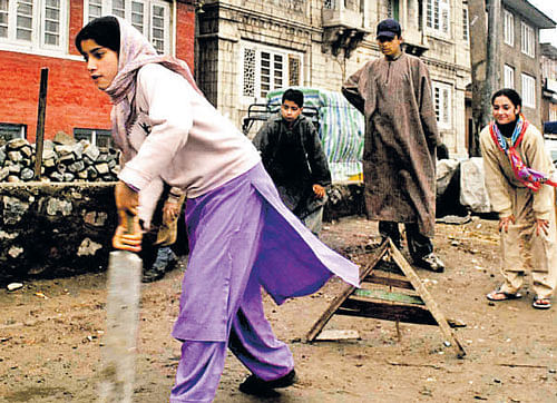 Young girls playing cricket.