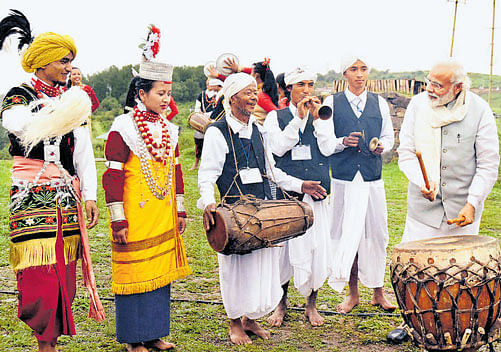 Prime Minister Narendra Modi tries his hands at a drum in Heritage Mawphlang village in Meghalaya on Saturday. PTI