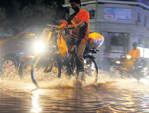 A cyclist struggles to negotiate a waterlogged  road in the city on Saturday. City recorded 7.4 mm of rain in evening. dh photo