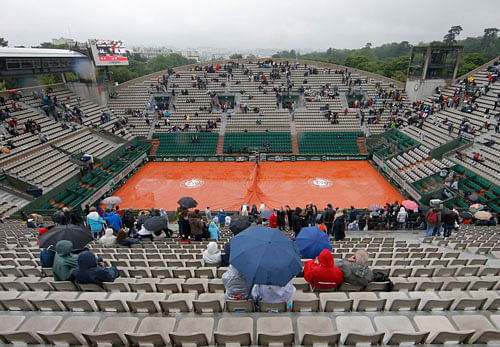 Spectators use umbrellas to protect themselves from the rain. REUTERS