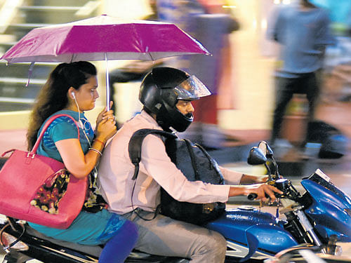 A couple takes protection under an umbrella during a drizzle on Commercial Street in  Bengaluru on Wednesday. DH Photo
