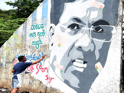 Artist Paramesh Jolad  paints a portrait of Chief  Minister Siddaramaiah at  the Vijayanagar bus stop on Friday. DH&#8200;PHOTO