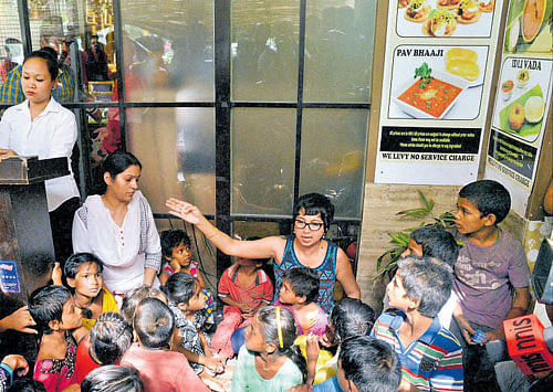 Sonali Shetty and street children sit outside a restaurant after they were refused service, in New Delhi on Sunday. PTI