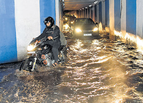 A biker struggles through an inundated underpass near  Le Meridien Hotel. DH PHOTO