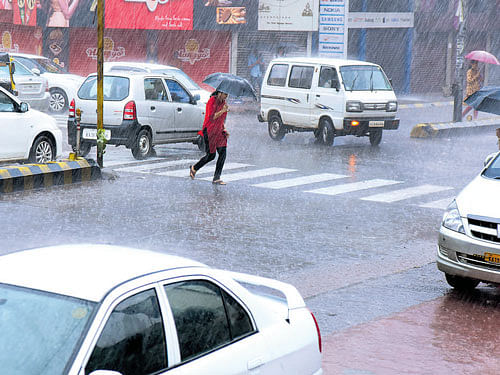 A woman crossesMG Road as heavy rain lashed Mangaluru on Saturday. DH PHOTO