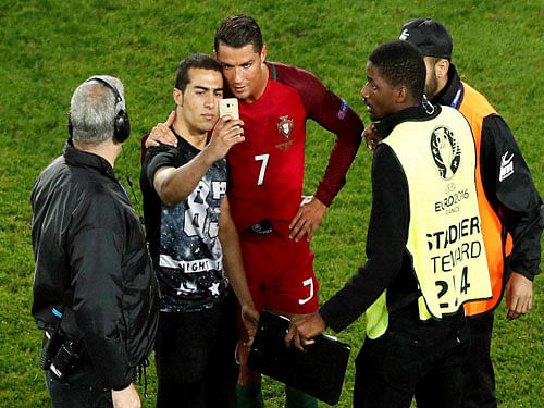 Portugal's Cristiano Ronaldo poses for a selfie with a man who invaded the pitch at the end of the Euro 2016 Group F soccer match between Portugal and Austria at the Parc des Princes stadium in Paris, France. AP/PTI