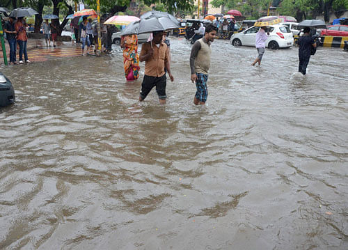 Monsoon effect: People walk through a waterlogged road following heavy downpour in Navi Mumbai. PTI