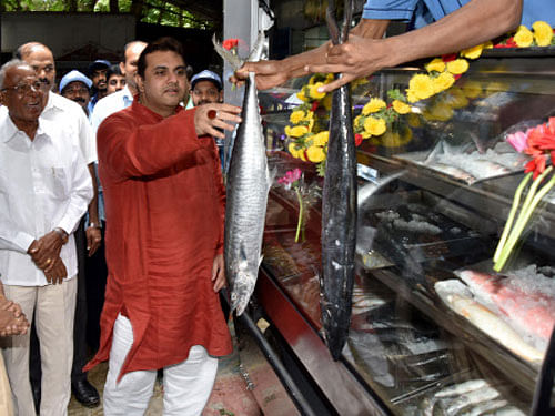 Pramod Madwaraj, Youth Service and Fisheries minister, holds fish during the  inauguration of 'Mobile Matyadarshini' in Bengaluru on Thursday.