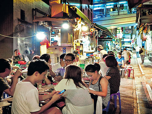 Locals enjoying street food at a 'dai pai dong', an open-air food stall.
