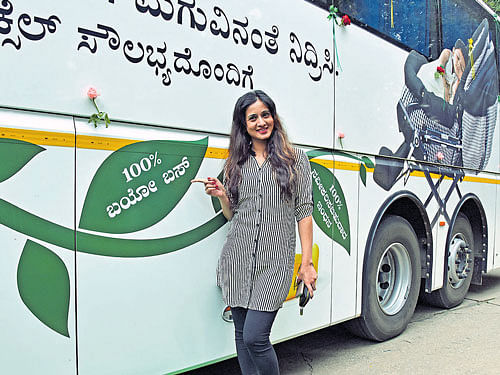 Actor Harshika Poonacha poses near a biobus in Bengaluru on Monday. The bus, operating between Bengaluru and Chennai, runs completely on biodiesel. dh photo