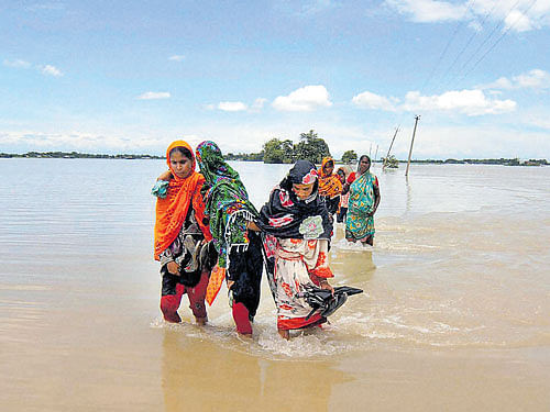 knee-deep: Women wade through a flood-affected village in Morigaon, Assam, on Wednesday. PTI