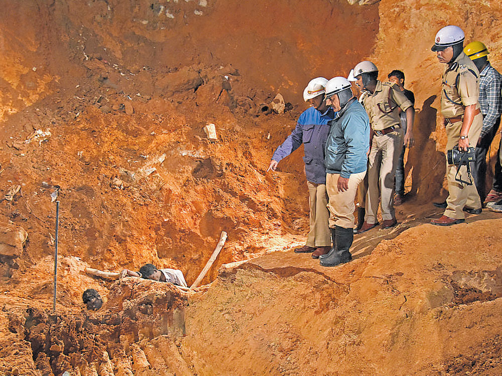Fire and Emergency Service personnel retrieve the bodies of the three labourers who were buried alive after the foundation of a building under construction collapsed in Koramangala 7th Block on Saturday. DH photo