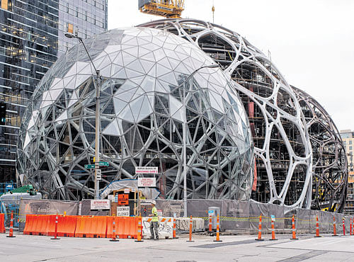 THE 'GREEN' GLOBE: Transparent, conjoined structures that Amazon calls spheres, under construction in Seattle. Amazon is building a complex at its Seattle headquarters where employees can sit by a creek, walk on suspension bridges and brainstorm in the boughs. NYT