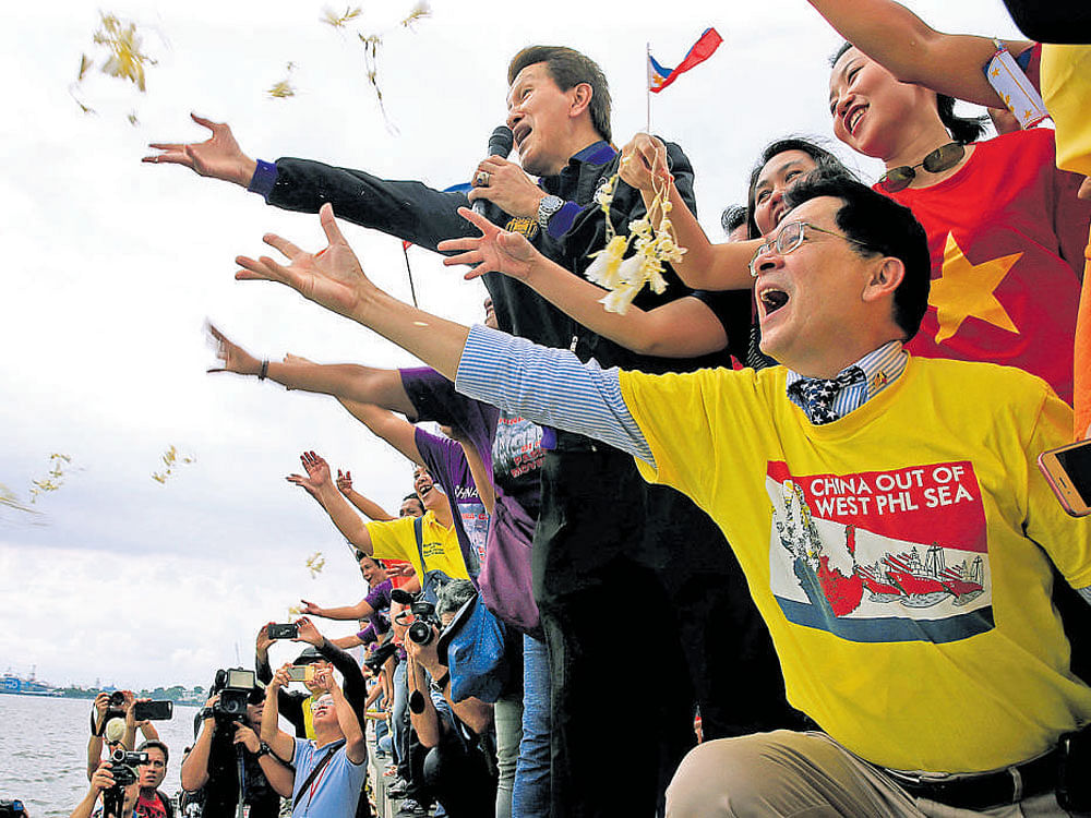 Protesters throw flowers while chanting anti-Chinese slogans during a rally by different activist groups over the South China Sea disputes, along a bay in metro Manila, the Philippines, on Tuesday. Reuters