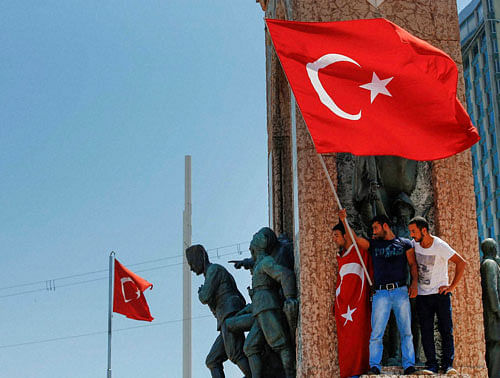 People protesting against the coup, wave a Turkish flag on top of the monument in Taksim square, Istanbul, Turkey, Saturday, July 16, 2016. Turkish President Recep Tayyip Erdogan told the nation Saturday that his government is in charge after a coup attempt brought a night of explosions, air battles and gunfire across the capital that left dozens dead. The state-run news agency said more than 750 soldiers have been detained across the country. AP/PTI