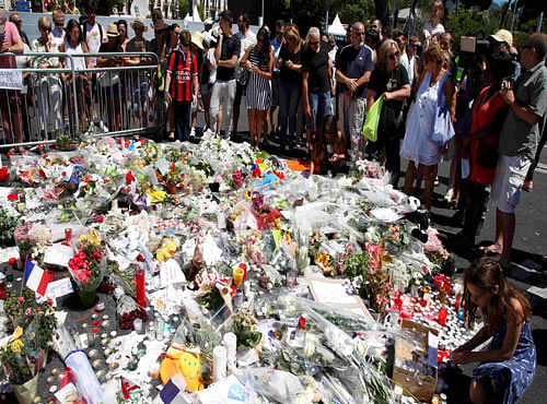 People gather around bouquets of flowers in tribute to victims, two days after an attack by the driver of a heavy truck who ran into a crowd on Bastille Day killing scores and injuring as many, in Nice. Reuters photo