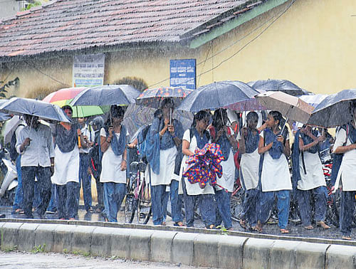 Schoolgirls head home amid rain in Karwar on Monday. DH Photo