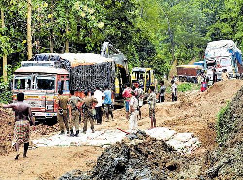 ATTEMPT TO SALVAGE: Workers try to move vehicles stuck on the damaged National Highway 44 due to the heavy landslides at Khasiapunji in Karimganj district, Assam on Wednesday. PTI
