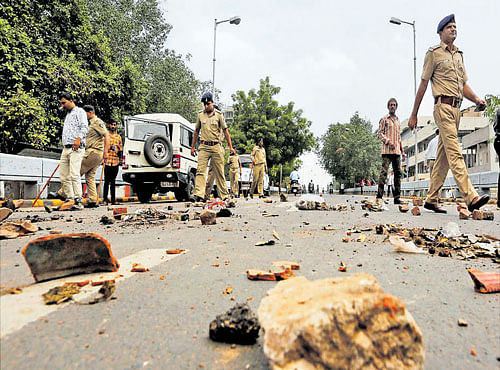 Policemen remove stones put by members of the Dalit community to block traffic during their protests in Ahmedabad on Wednesday. PTI