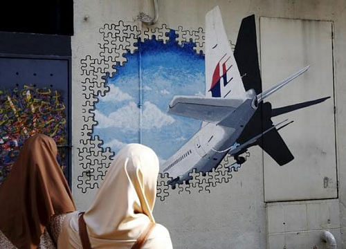 Women look at a mural of missing Malaysia Airlines flight MH370 two years after it disappeared, in Kuala Lumpur, Malaysia, March 7, 2016. Reuters