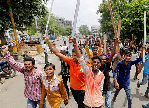 Dalit community member hold wooden sticks and shout slogans during a protest in Ahmedabad on Wednesday. They were protesting after four men belonging to the Dalit community were beaten up while trying to skin a dead cow in Una town in Gujarat last week. PTI Photo