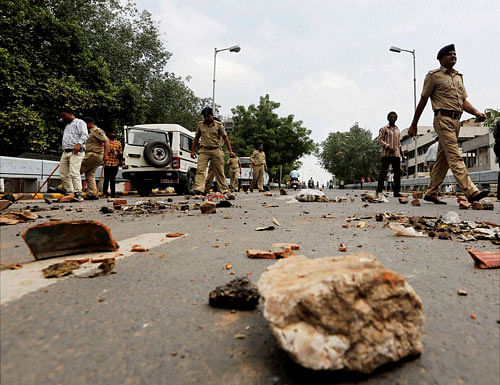 Policemen remove stones put by members of Dalit community to block traffic during their protests in Ahmedabad on Wednesday. They were protesting after four men belonging to the Dalit community were beaten up while trying to skin a dead cow in Una town in Gujarat last week. PTI Photo