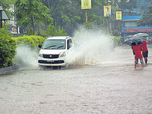 A car navigates on the inundated Green Street Road in  Karwar as heavy rain lashed the town on Sunday. DH Photo
