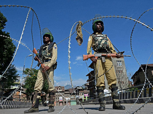 CRPF Jawans guard near razor wires during curfew and strike in Srinagar. PTI Photo.
