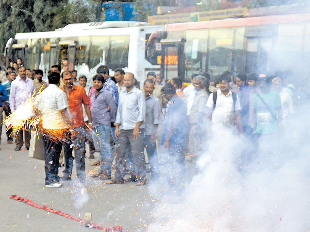 Members of the State Transport Unions celebrate by bursting crackers at the Kempegowda Bus Station in Bengaluru after the bus strike was called off on Wednesday. DH