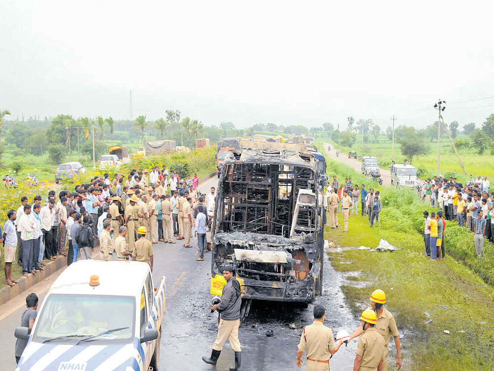A crowd gathers near the non-AC sleeper bus belonging to Durgamba Travels which caught fire near Varur in Hubbali taluk in the wee hours of Wednesday. DH