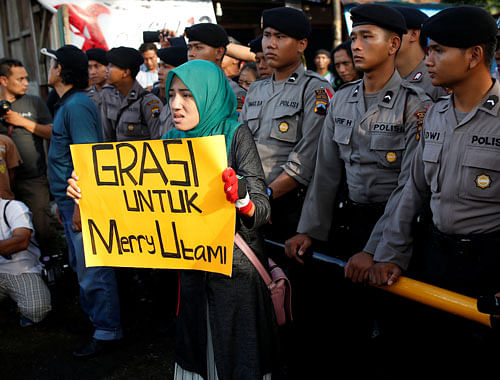 A woman holds a placard which reads 'Clemency for Merry Utami', a death-row prisoner, near the gate to the ferry port for the prison island of Nusa Kambangan island, ahead of the expected execution of 14 drug convicts in Cilacap, Central Java, Indonesia July 28, 2016. REUTERS