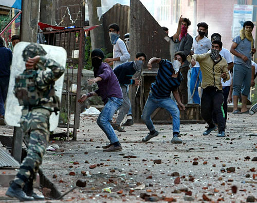 Security jawan chasing away protesters throwing stones at them during a clash in Srinagar on Thursday.PTI Photo