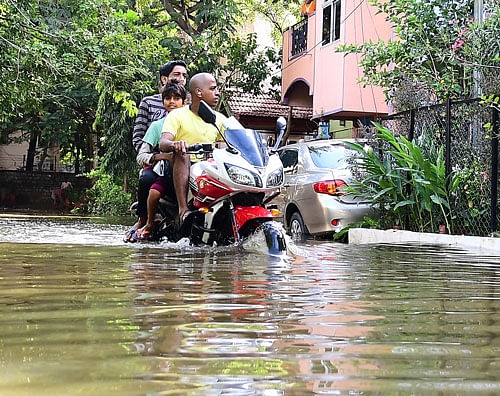 On day two: Bike-borne residents ride on a waterlogged stretch in BTM Layout after the Madiwala lake overflowed. DH Photo