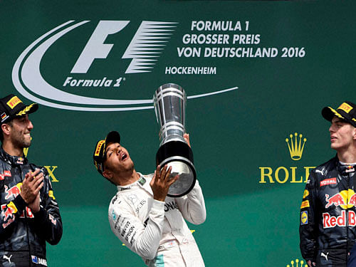 Red Bull driver Daniel Ricciardo of Australia, left, and Red Bull driver Max Verstappen, watch as Mercedes driver Lewis Hamilton of Britain lifts his trophy on the podium at the end of the German Formula One Grand Prix in Hockenheim, Germany, Sunday, July 31, 2016. Hamilton won the race, Ricciardo was second and Verstappen was third. AP/PTI