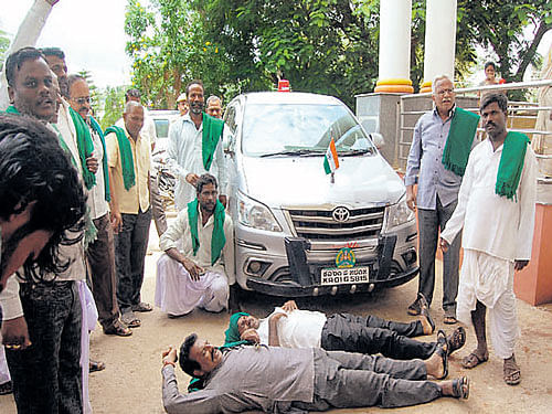 Members of the Raitha Sangha and the Hasiru Sene lie down in front of Rural Development and Panchayat Raj Minister H&#8200;K&#8200;Patil's car in Gadag on Sunday, to protest the police excesses in Navalgund.dh photo