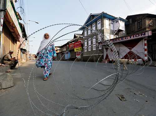 A Kashmiri woman walks behind concertina wire during a curfew in downtown Srinagar, August 1, 2016. REUTERS
