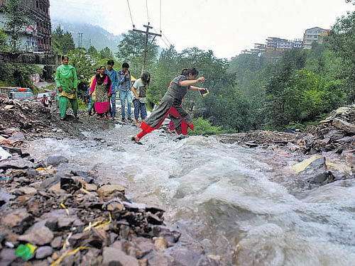 Girls cross a flooded road in Shimla on Monday. PTI