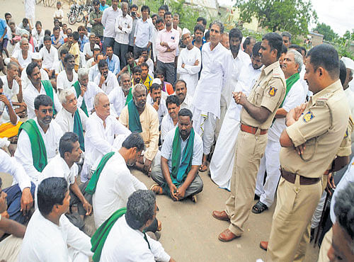 Police officers speak to protesting farmers at Belagal village, Hungund taluk of Bagalkot district, on Monday. DH PHOTO