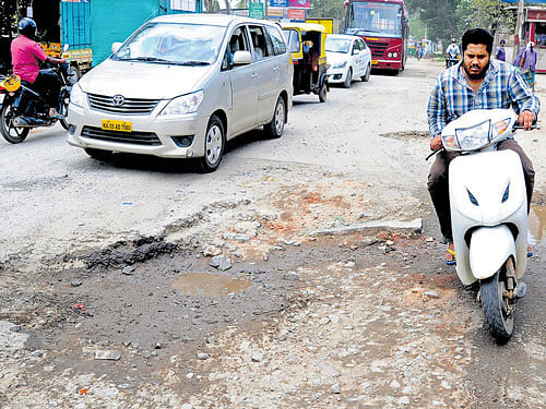 A scooterist has to do a balancing act passing through a stretch damaged by rain on the Bannerghatta main road in Gottigere. DH Photo