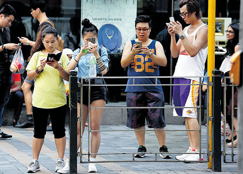 leading the way: People use their smartphones on a street in Hong Kong. In China, more people use their mobile devices to pay their bills, order services, watch videos and find dates than anywhere else in the world today. REUTERS