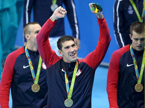 Michael Phelps poses with his gold medal as he celebrates with his team. REUTERS
