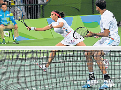 FOCUSED: India's Sania Mirza returns as partner Rohan Bopanna looks on in their mixed doubles tie. DH PHOTO/ K N Shanth kumar