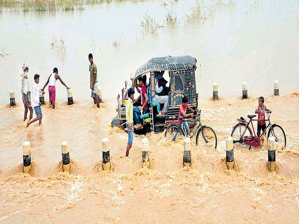 People in a flooded locality near Patna on Sunday. PTI