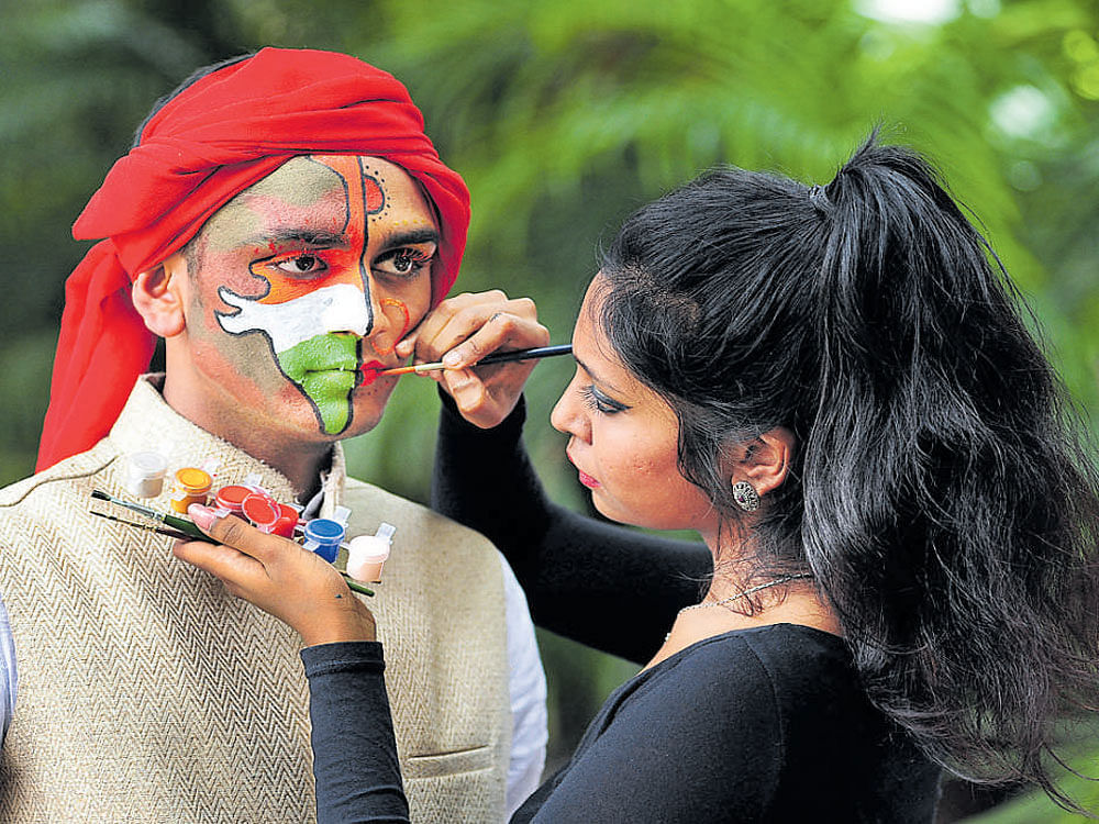 A student at JD Institute of Fashion Technology paints the Indian map on a man's face at a cultural programme as part of Independence Day celebrations in Bengaluru on Monday. DH photo