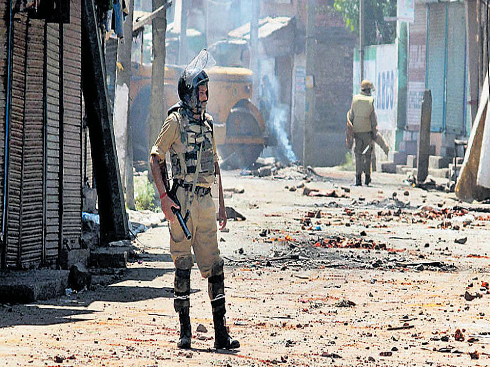 Security personnel guard a deserted street at Batamaloo during curfew in Srinagar on Tuesday. PTI