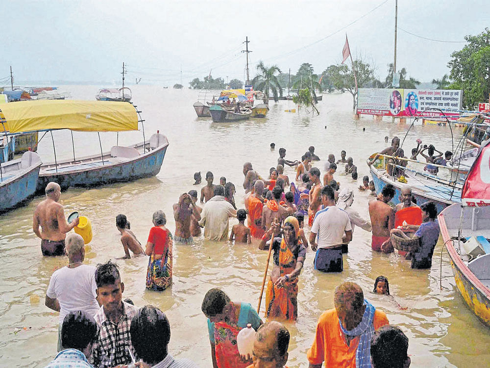 People try to cross a road flooded by Ganga and Yamuna rivers in Allahabad. PTI