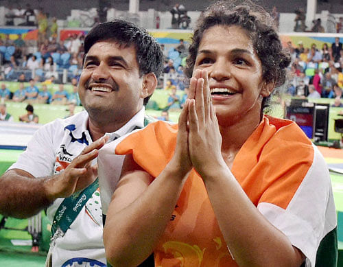 India's Sakshi Malik with her coach Kuldeep Singh, celebrate after winning bronze against Kyrgyzstan's Aisuluu Tynybekova in the women's wrestling freestyle 58-kg competition, at the 2016 Summer Olympics in Rio de Janeiro, Brazil on Wednesday. PTI Photo