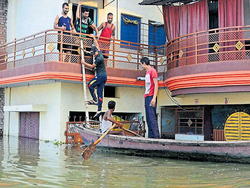 Residents move out of a flooded house in Allahabad. PTI photo.